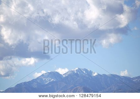 The snowcapped peak of Mount San Jacinto in the San Jacinto Mountains with clouds over the mountains.