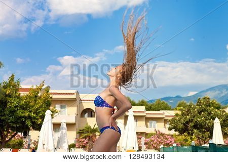 Girl in a blue bathing suit and long hair flying in the resort