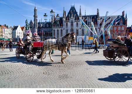 Bruges, Belgium - April 10, 2016:  Fiaker with tourists in Market place or Grote Markt square,  popular belgian destination Brugge, Belgium