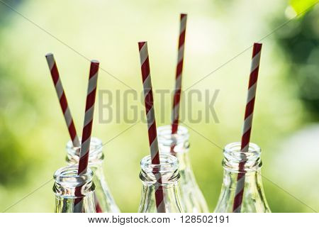 Glass Bottles With Straws Over The Sunny Background