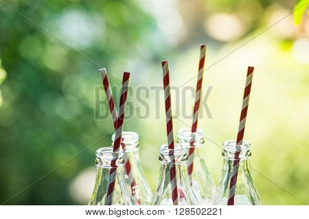 Glass Bottles With Straws Over The Sunny Background