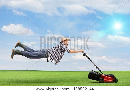 Mature man being pulled by a powerful lawnmower outdoors on a beautiful sunny day