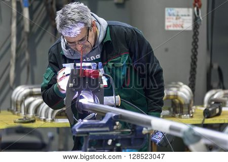 Industrial operator setting  computer controlled process of orbital welding machine in  stainless steel pipes manufacturing workshop.