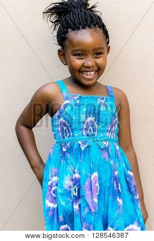 Close up candid snapshot of Laughing african girl in front of wall outdoors.