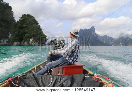 Suratthani Thailand - April 14 2015: Boat driver was on the back of long tail boat  speeding on green water of dam called 'Ratchaprapha' in Suratthani Thailand.