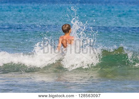 Young boy on the beach  having fun with the waves