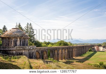 Ancient cistern in Tuscany and Nottolini Aqueduct leading past a country villa and toward the distant mountains. Copy space in sky if needed. Concepts could include Travel Architecture Europe others.