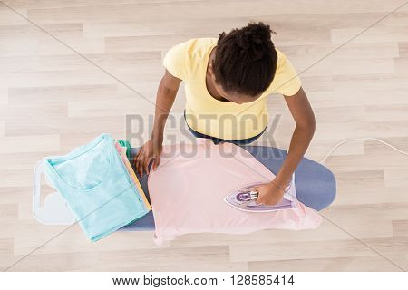 High Angle View Of African Woman Ironing Clothes On Ironing Board
