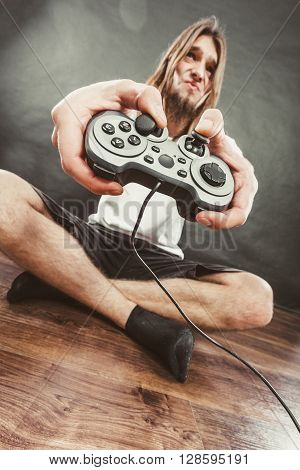 Addiction effects concept. Young unhappy depressed man with pad joystick playing games. Male addicted to console playstation videogames.