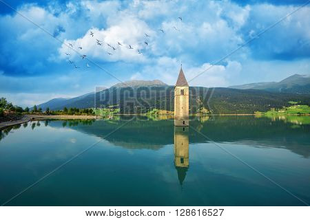 Beautiful view of the lake Resia. Famous tower in the water. Alps, Italy, Europe.