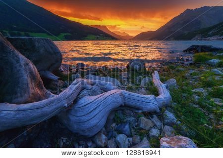 Beautiful view of the lake Resia. Dramatic sky and colorful sunset. Alps, Italy, Europe.