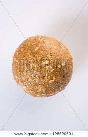 tilgul or til gul laddu, isolated on white background, showing wooden plate full of laddu in background, selective focus