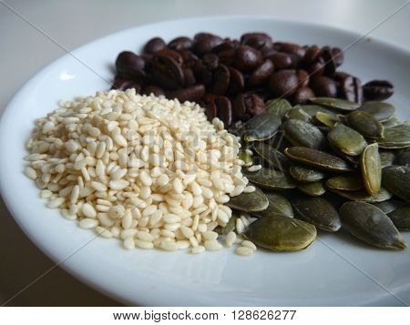 Gourd And Sesami Seed With Coffee Beans On A White Plate
