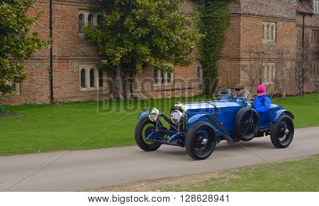 Saffron Walden, Essex, England - April 24, 2016: Vintage blue racing car being driven past  front of old building.