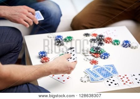 leisure, games, friendship, gambling and entertainment - close up of male friends playing cards at home