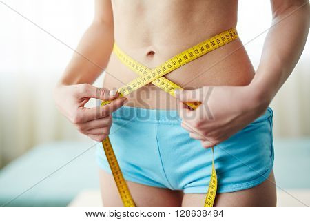 Youg woman measuring her waist