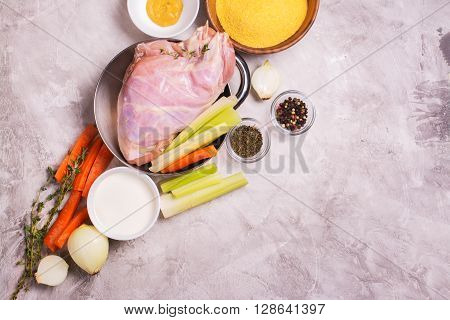 Raw rabbit legs, vegetables, spices and polelnta over stone table. Top view