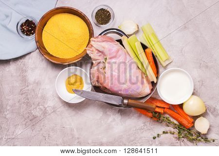 Raw rabbit legs, vegetables, spices and polelnta over stone table. Top view