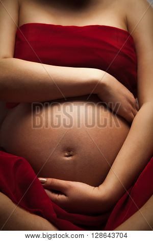 Pregnant woman is putting hands on her belly.