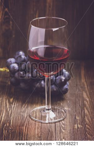 Glass of red wine and grapes. Toned vintage image. Selective focus