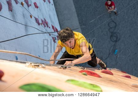 Elderly Female Demonstrates Excellent Physical and Mental Abilities Ascending Vertical Climbing Wall Belaying Partner Staying Below on Remote Ground