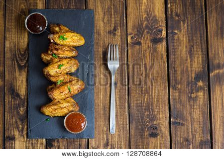 Chicken wings on a slate plate on wooden background