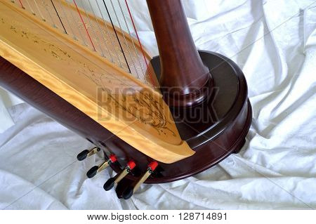 Closeup of the base of a dark wood concert grand pedal harp. Pedals and soundboard in detail.