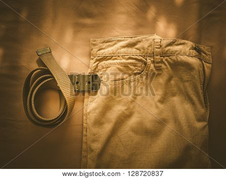 Vintage chino pants and army belt for men on fabric background