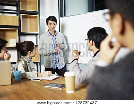 young asian businessman facilitating a group discussion or training in office.