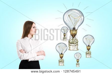 Success concept with businesswoman looking at lightbulb airballoons with money nags