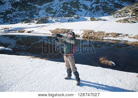 brunette woman with green red and brown clothes with camera as photographer taking selfie photo picture in winter snow Gredos mountain Avila Spain Europe