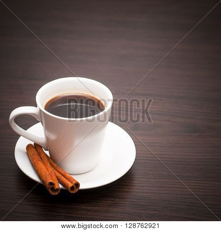 White cup of coffee with vanilla on a dark wooden background