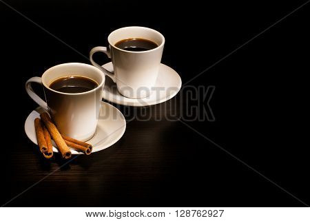 Two white cups of coffee with vanilla on a dark wooden background
