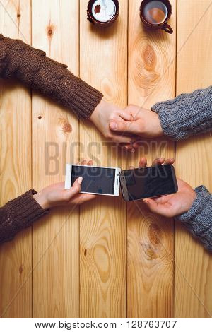 Couple drinking tea with lemon, with a phone in his hand. holding hands. top view