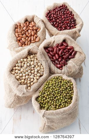 Assortment Of Beans And Lentils In Hemp Sack On Wooden Background. Green Bean, Groundnut, Soybean, R