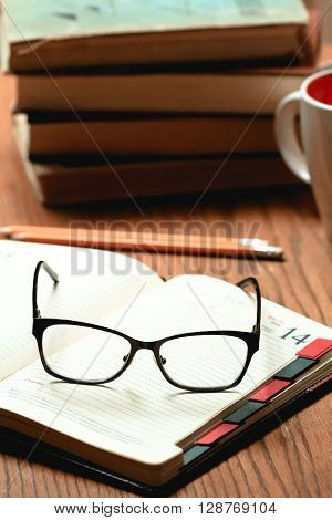 Glasses, book and cup of tea on a wooden table