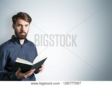 Bearded caucasian male with open book on light grey background. Mock up