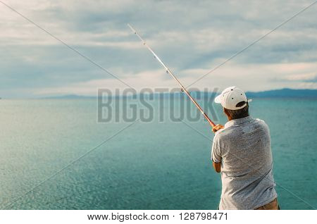 PEFKOHORI GREECE - MAY 26 2015: Man wearing a cap is back and fishing in the Aegean sea