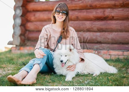 young stylish hipster woman girl playing white kid-skin dog in country side.