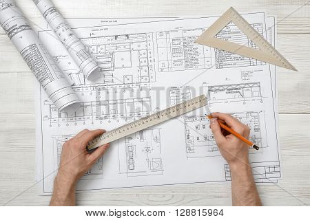 Close-up of architect hands holding centimeter ruler and pencil. Measuring process. Work place of draftsman, architect, constructor. Working process. Engineering work. Construction and architecture. Architect drawing. Measurement.