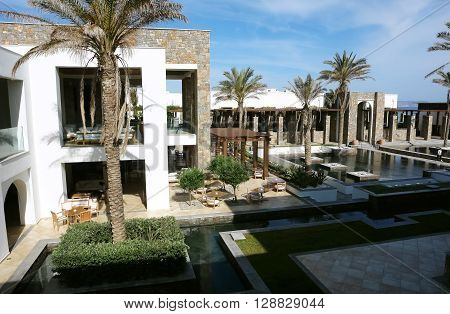 HERAKLION, CRETE, GREECE - MAY 13, 2014: The blue sky swimming-pool modern building with columns and palms in luxury class hotel Grecotel Amirandes on the Mediterranean coast of Crete, May 13, 2014, Greece.