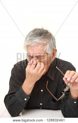 senior Japanese man suffers from Asthenopia on white background