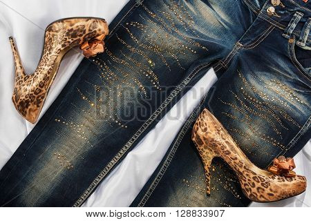 Glamorous women's fashion leopard shoes lying on jeans view from above