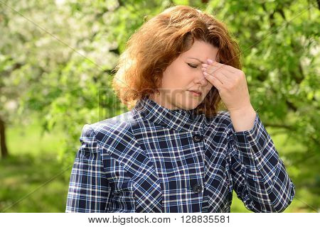 A woman with a headache on the nature of the spring