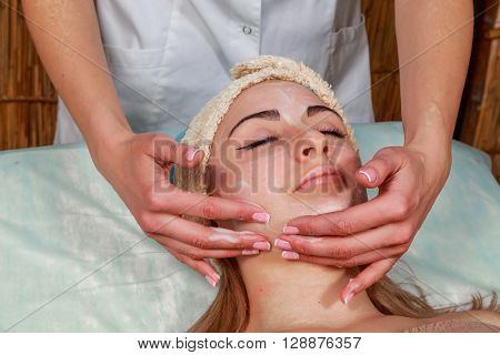 Girl with a beautician at spa salon. Beautician performs cosmetic procedures.applying cosmetic cream. Cosmetology facial beauty - The concept of facial skin care. Article about cosmetology.