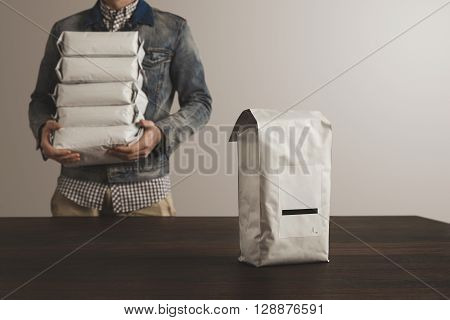 Big Sealed Hermetic Blank Labeled Package Presented In Focus In Front Of Unfocused Worker Man Loded