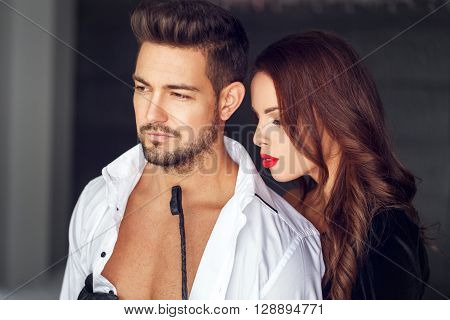 Sexy dominatrix playing with macho lover indoor