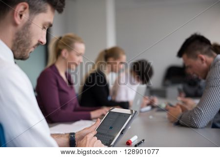 close up of  businessman hands  using tablet, people group in office meeting  room blurred in backgronud