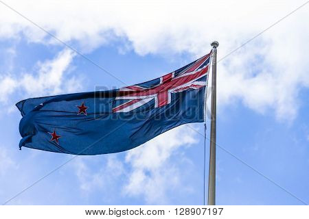 Australian flag waving against a blue sky with white clouds