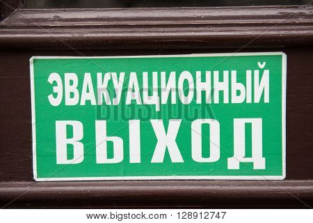 A signboard written in russian language hanging on a building gate. Exit sign.